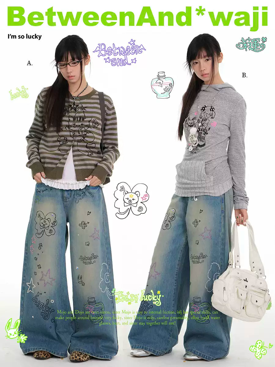 ラインストーンのディテールとウォッシュ仕上げが施されたブルーのグラフィティプリントジーンズ